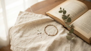 Christlicher Schmuck: feine Silberkette mit Kreuz und Perlenarmband auf hellem Leinen