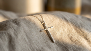 Feine silberne Jesus Kreuzkette auf Leinenstoff im warmen Licht